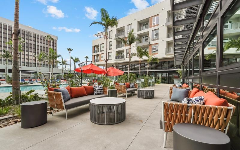 a patio with lounge chairs and umbrellas next to a pool